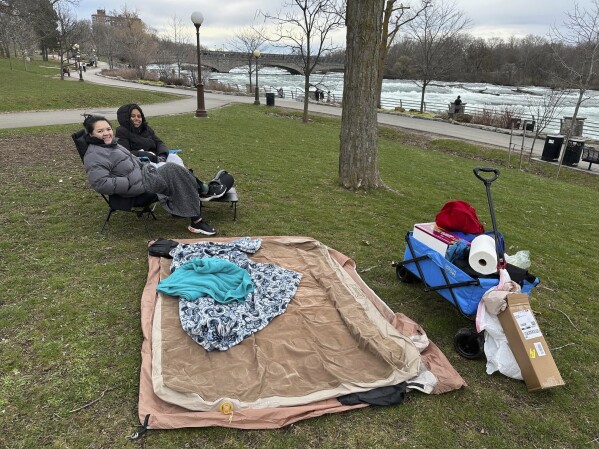 Synthia Nguyen and Jen Cerna from Washington, DC, claimed a prime spot on the lawn along the rapids in Niagara Falls State Park, to view the solar eclipse, Monday, April 8, 2024, in Niagara Falls, N.Y. (AP Photo/Carolyn Thompson)